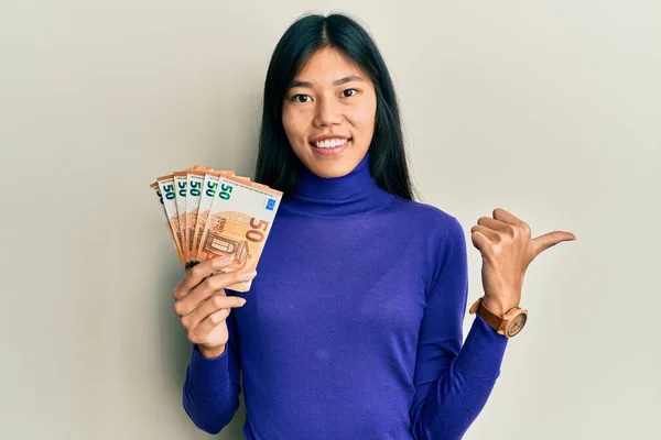 Jovem Asiática Segurando Maço Notas Euro Apontando Polegar Para Lado — Fotografia de Stock