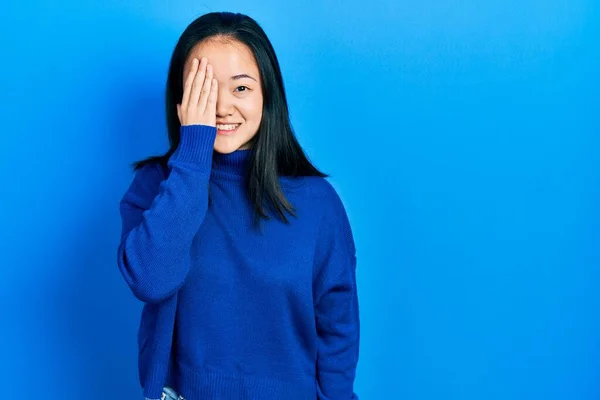 若い中国の女の子は手で一つの目をカバーカジュアル服を着て 顔に自信を持って笑顔と驚きの感情 — ストック写真