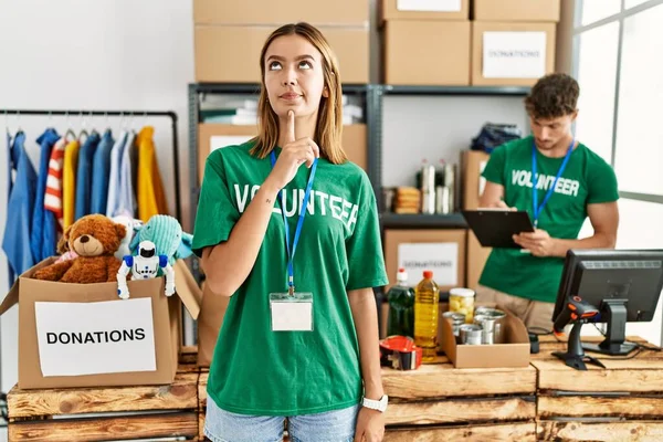 Joven Chica Rubia Vistiendo Camiseta Voluntaria Puesto Donación Pensando Concentrado —  Fotos de Stock