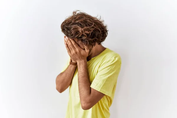 泣きながら手で顔を覆う悲しい表情で孤立した背景の上に立つ若いヒスパニック系の男 うつ病の概念 — ストック写真