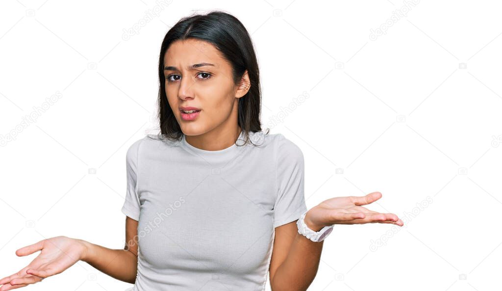 Young hispanic girl wearing casual white t shirt clueless and confused with open arms, no idea concept. 