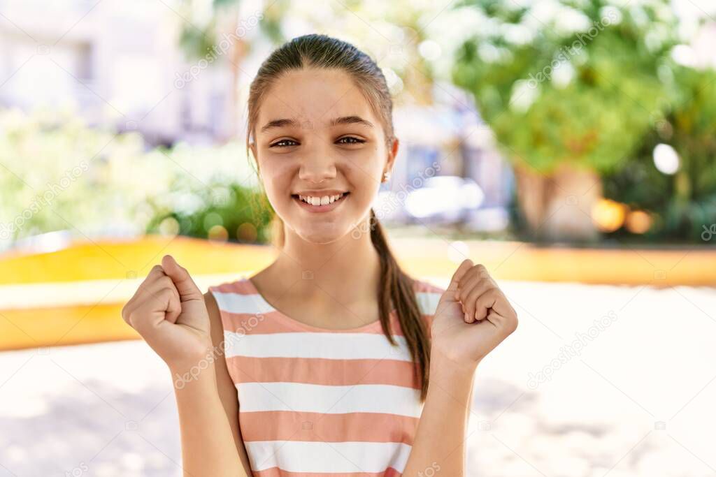 Young teenager girl outdoors on a sunny day screaming proud, celebrating victory and success very excited with raised arms 