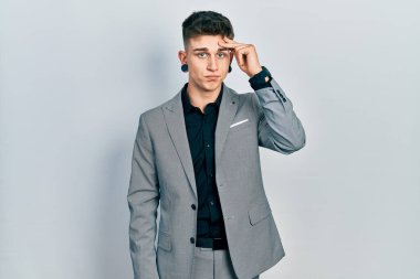 Kulakları genişlemiş, iş ceketi giymiş, alnında bir sorun olduğu için endişeli ve stresli genç bir beyaz çocuk. Kriz için endişeli. 