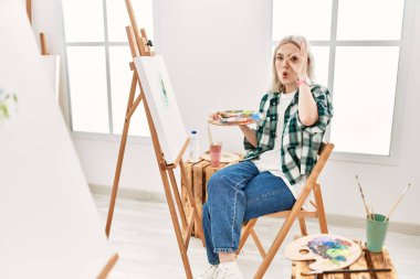 Sanat stüdyosunda resim yapan genç sanatçı kadın şaşırmış yüz ifadesiyle şok olmuş, parmaklarından bakan gözler. İnançsız ifade. 