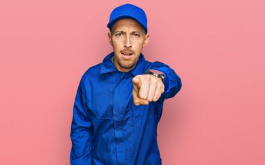 Sakallı, inşaatçı tulumu giymiş kel bir adam kameraya kızgın ve sinirli olduğunu gösteriyor. 