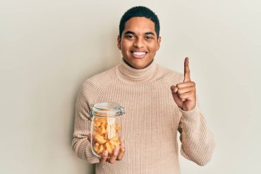 Genç, yakışıklı İspanyol adam elinde makarna kavanozuyla gülümseyen bir fikir ya da soru işareti ile gülümseyen mutlu bir yüz, bir numara. 