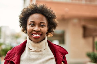 Güzel bir iş adamı Afro saçlı Amerikalı kadın şehirde mutlu ve kendinden emin bir şekilde gülümsüyor.