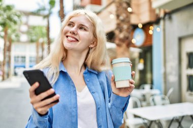 Genç sarışın kadın güneşli bir günde akıllı telefon kullanıyor.