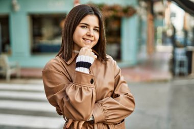 Genç, güzel, esmer kadın dışarıda mutlu bir şekilde gülümsüyor.