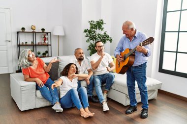Bir grup orta yaşlı arkadaş evdeki kanepede oturup klasik gitar çalıyorlar..