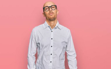 Sakallı, iş gömleği giyen ve gözlüklü kel bir adam. Yüzünde ciddi bir ifadeyle rahatlamış. Basit ve doğal bir şekilde kameraya bakıyorsun.. 