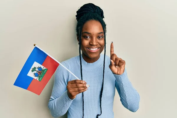 アフリカ系アメリカ人女性と編組髪を保持Haitiフラグ笑顔でアイデアや質問を指差す指で幸せな顔 第1位 — ストック写真