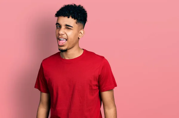 Joven Hombre Afroamericano Vistiendo Casual Camiseta Roja Guiño Mirando Cámara — Foto de Stock