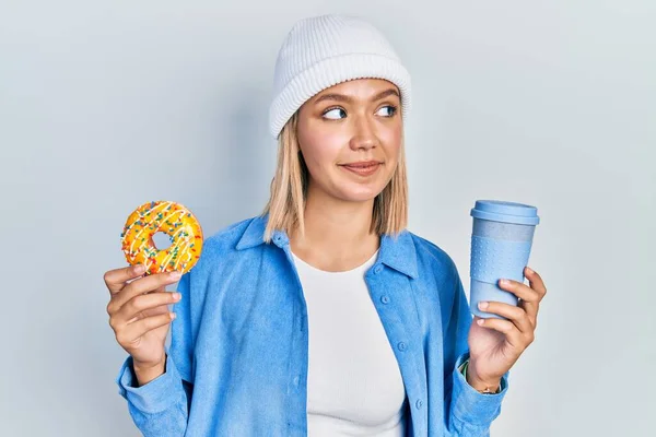 Mulher Loira Bonita Comendo Donut Bebendo Café Sorrindo Olhando Para — Fotografia de Stock