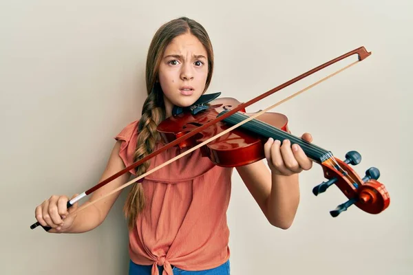 美丽的黑发小女孩弹奏小提琴时充满怀疑和紧张 皱着眉头因问题而烦躁不安 消极的人 — 图库照片