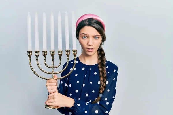 Jovem Morena Segurando Menorah Hanukkah Vela Judaica Rosto Choque Olhando — Fotografia de Stock