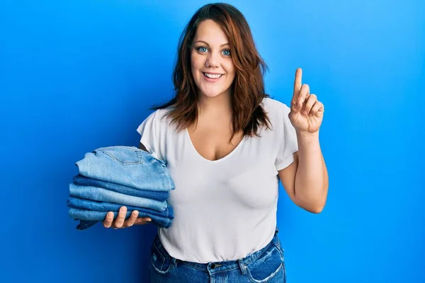 Young Caucasian Woman Holding Stack Folded Jeans Smiling Idea Question — Stock Photo, Image