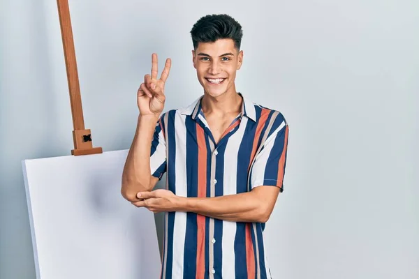 Joven Hombre Hispano Pie Cerca Lienzo Vacío Sonriendo Con Cara — Foto de Stock