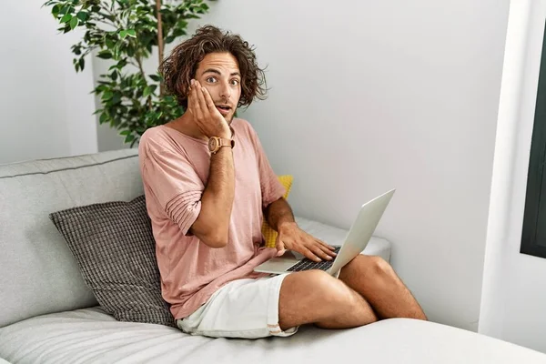 Young Hispanic Man Sitting Sofa Home Using Laptop Afraid Shocked — Stock Photo, Image