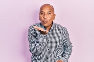 Orta yaşlı, sıradan kıyafetler giyen, kameraya bakıp havada el sallayan Latin bir adam. Güzel ve seksi. aşk ifadesi. 