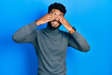 Balıkçı yaka kazak giyen, elleri gülücüklü, komik gözlü Arap bir adam. kör kavram. 