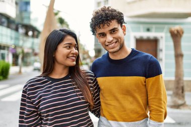 Genç Latin çift gülümsüyor ve şehirde sarılıyorlar..