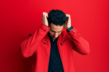 Kırmızı deri ceket giyen genç İspanyol adam acı ve migren yüzünden çaresiz ve stresli bir şekilde baş ağrısı çekiyor. Eller başının üstünde.. 