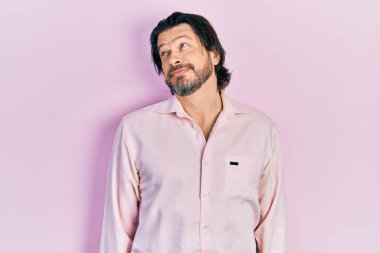 Orta yaşlı, günlük kıyafetler giyen, gülümseyen ve kafasını çeviren beyaz bir adam.. 