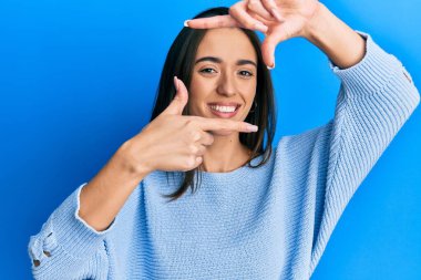 Gündelik kıyafetler giyen, gülümseyen, elleri ve parmakları gülen yüzlü, çerçeveli genç İspanyol kız. yaratıcılık ve fotoğrafçılık kavramı. 