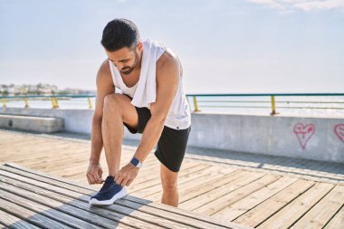 İspanyol adam güneşli bir günde dışarıda çalışıyor, bağcıklarını bağlıyor.