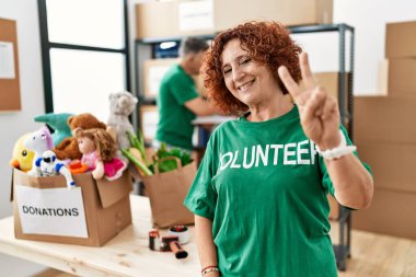 Bağışta gönüllü tişört giyen orta yaşlı kadın kameraya bakıp zafer işareti yaparken gülümsüyor. İki numara.. 