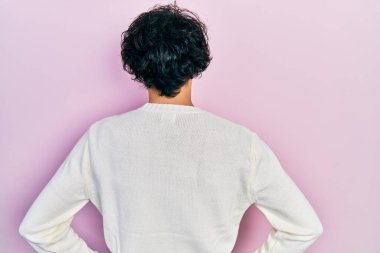 Yakışıklı, beyaz süveter giyen, kolları vücudunda geriye bakan İspanyol bir adam. 