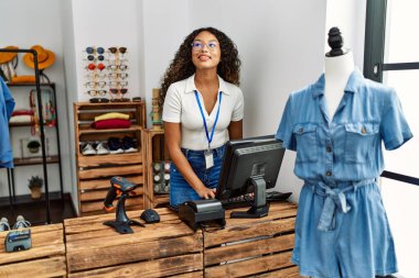 Genç Latin esnaf kadın giyim mağazasında bilgisayar kullanıyor..