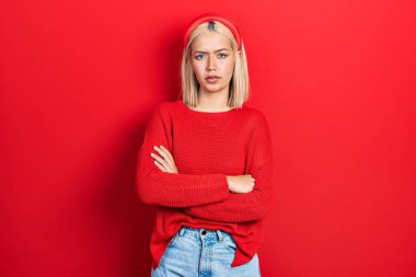 Güzel sarışın kadın, sıradan kırmızı süveter giyiyor. Kuşkucu ve gergin. Yüzünde çapraz kollu tasvip etmeyen bir ifade. negatif kişi. 