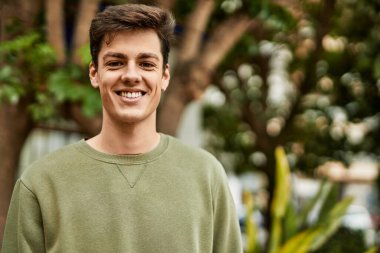 Genç İspanyol adam gülümseyerek şehirde mutlu mesut dikiliyor..