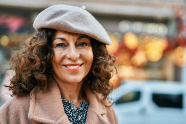 Orta yaşlı İspanyol kadın gülümseyerek şehirde mutlu mesut dikiliyor..