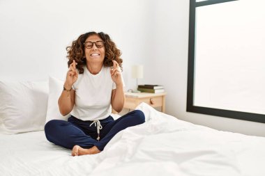 Orta yaşlı İspanyol bir kadın evde yatağında oturmuş umut ve gözlerin kapalı gülümseyerek el sallıyor. Şans ve batıl inançlar. 