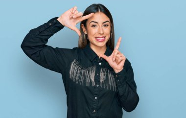 Gündelik kıyafetler giyen, gülümseyen, elleri ve parmakları gülen yüzlü genç İspanyol kadın. yaratıcılık ve fotoğrafçılık kavramı. 