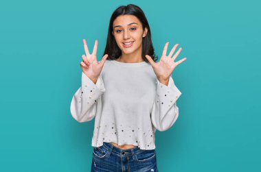 Gündelik kıyafetler giyen genç İspanyol kız gülümseyerek kendinden emin ve mutlu bir şekilde sekiz numarayı gösteriyor ve işaret ediyor.. 