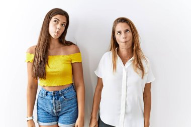 Anne ve kızı yalıtılmış arka planda birlikte durup dudaklarıyla balık suratı yapıyorlar, çılgınca ve komik bir jest. Komik ifade. 