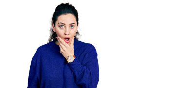 Gündelik kıyafetler giyen genç İspanyol kadın, elleri çenesinde, inanamama, şaşkınlık ve şaşkınlık dolu bir ifade takınıyor. 