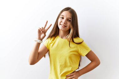 Genç esmer kız izole edilmiş arka planda yan yana durup kameraya bakıp zafer işareti yapıyor. İki numara.. 