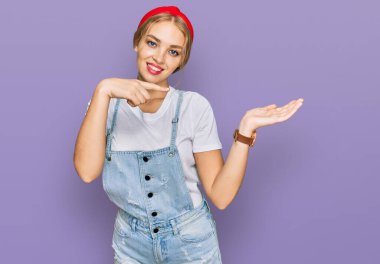 Gündelik giysiler giyen genç beyaz kız kameraya hayret ediyor ve gülümsüyor.. 