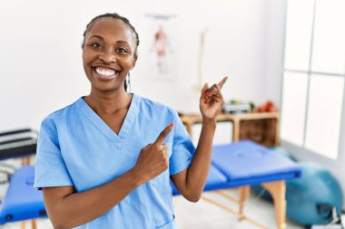 Saçları örgülü siyah bir kadın ağrı kesici kliniğinde çalışıyor gülümsüyor ve kameraya bakıyor.. 