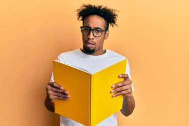 Sakallı, kitap okuyan, şok olmuş gözlüklü, şüpheci ve iğneleyici bakışlı, ağzı açık bir şekilde şaşırmış genç Afrikalı Amerikalı bir adam. 