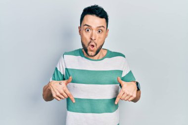 Gündelik giysiler giymiş genç İspanyol bir adam parmaklarını göstererek reklamını yapıyor, şaşırmış bir yüz ve ağzını açıyor. 