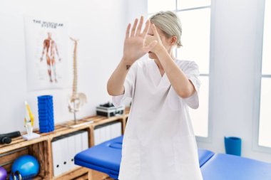 Ağrı giderme kliniğinde çalışan beyaz bir kadın elleriyle gözlerini kapatıyor ve üzgün ve korku ifadeleriyle jestleri durduruyor. utangaç ve olumsuz kavram. 