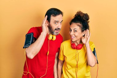 Orta yaşlı bir çift İspanyol kadın ve erkek spor giysisi ve kol bandı takmış kulakları kulaklarında dedikodu ve dedikoduları dinliyorlar. Sağırlık kavramı. 