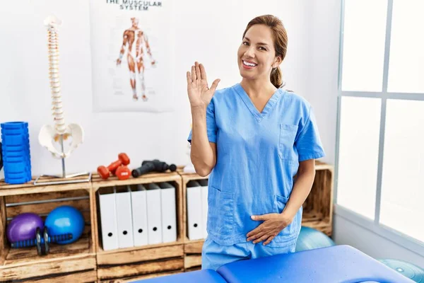Middle Age Hispanic Physiotherapist Woman Working Pain Recovery Clinic Waiving — Stock Photo, Image