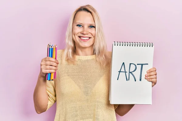 Hermosa Mujer Rubia Caucásica Sosteniendo Cuaderno Arte Lápices Color Sonriendo — Foto de Stock